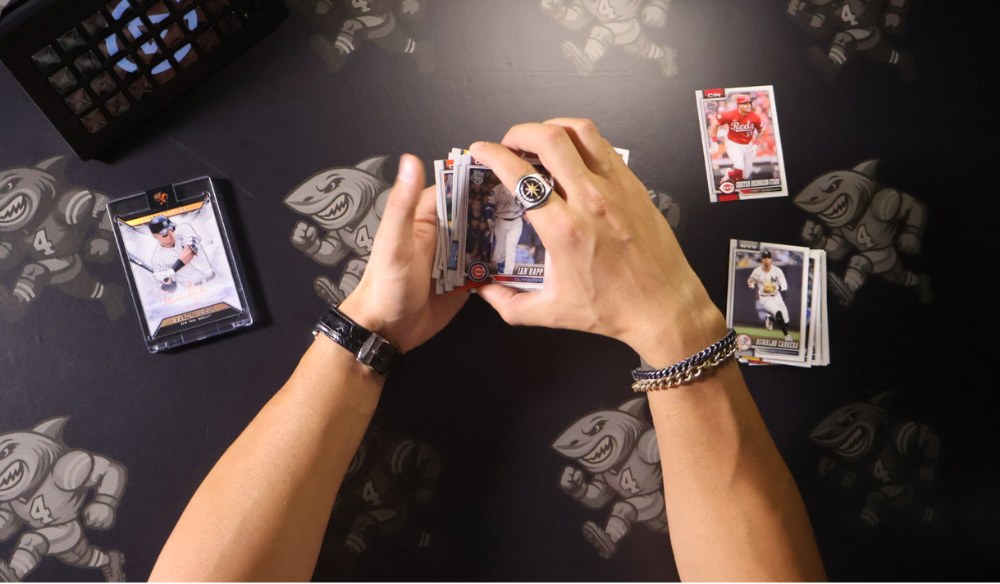 Hands opening a sports-card pack at a live breaking desk